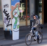 Une jeune fille à vélo devant un bonhomme de neige